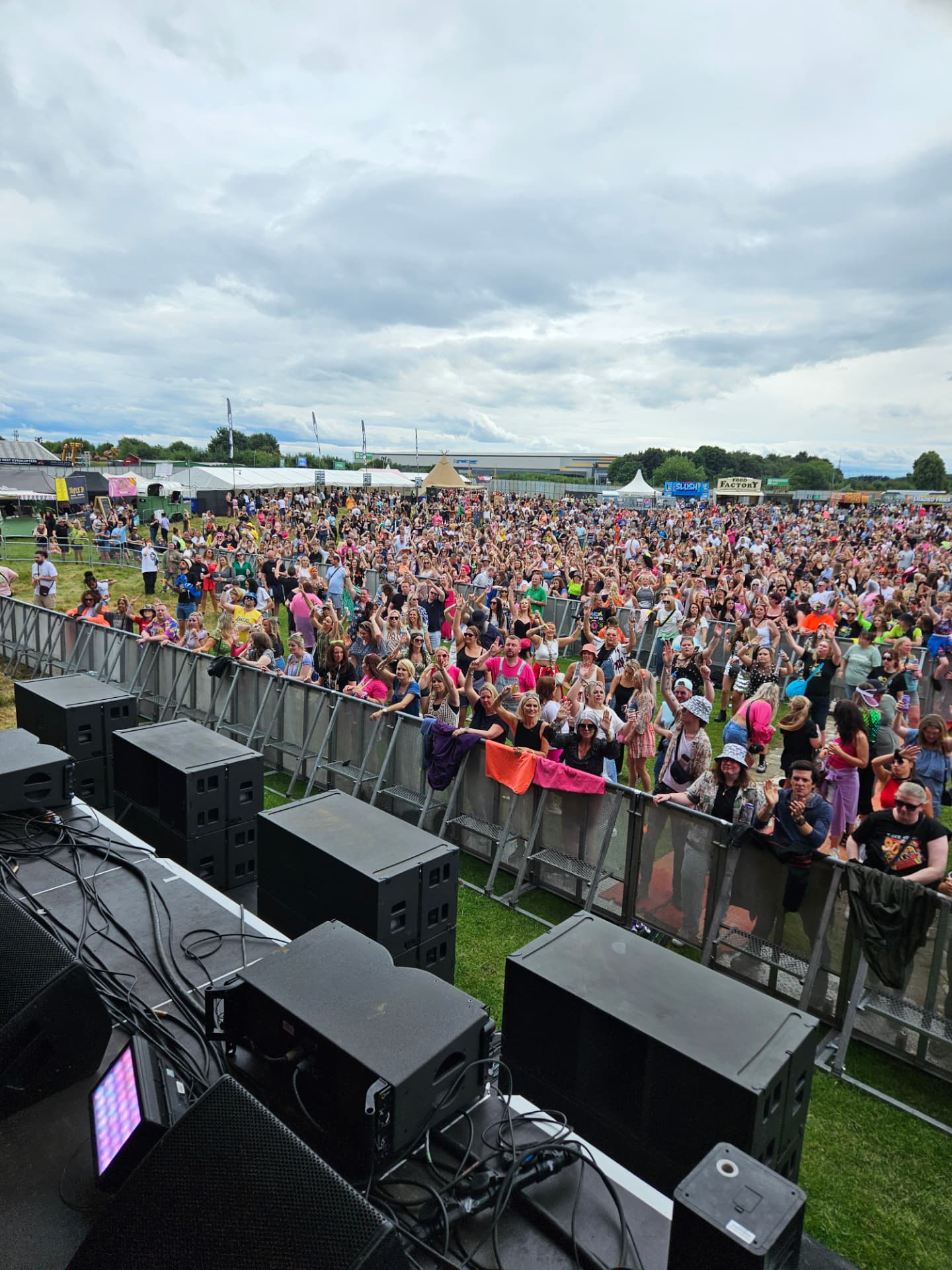 Stage view over the monitors to a daytime festival crowd